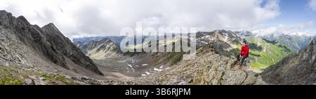 Panorama, mountaineer sitting on a rock, on a steep rocky ridge, on the summit of the Lasoerling, view of the mountain panorama of the Venediger group Stock Photo