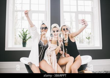 Picture showing group of happy friends in spa. girls with towels on heads having fun and taking selfie at home. Friendship, cosmetic, slumber party co Stock Photo