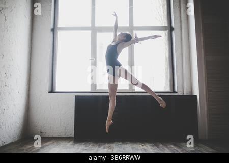 Plasticity slim woman dancing near window. Professional dancer enjoy dance. Lady Dancer Training Modern Ballet In Class. Contemporary dance performer. Stock Photo