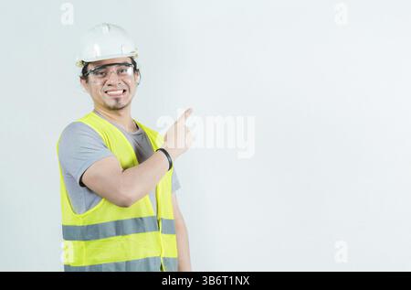 Happy male builder pointing to side isolated. Smiling male construction worker pointing blank space Stock Photo