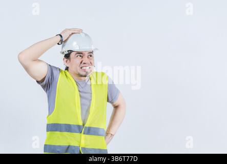 Constructor worker in problems holding head isolated. Worried builder engineer holding head. Troubled young engineer holding head Stock Photo