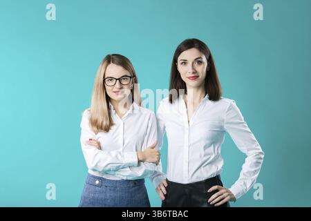The theme is a female team. portrait of two young caucasian business women posing in studio on a coloured background. Teamwork two people in office cl Stock Photo