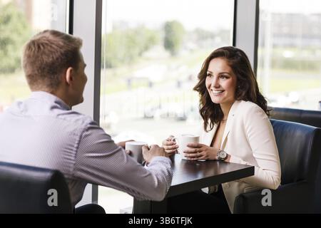 Couple enjoying coffee and talking in cafe Stock Photo