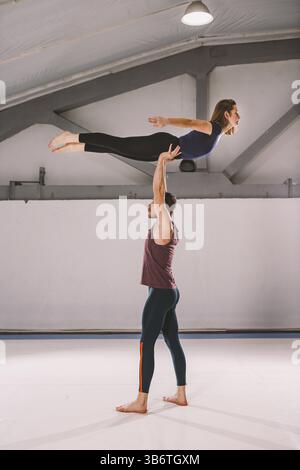 The theme of Acroyoga and Yoga Poses. A pair of two men and a woman stand in the position of asana. The guy holds the girl arched high back on the out Stock Photo