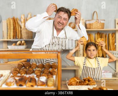 Uncle and girl are laughing, having fun, doing prank in trading floor of bakery store Stock Photo