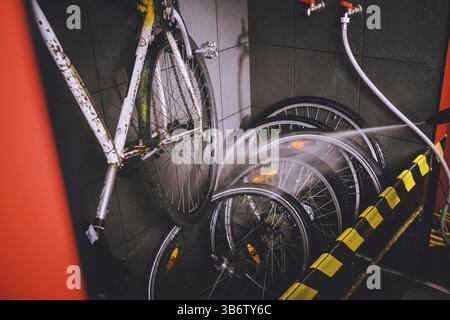 Services professional washing of bicycle in the workshop. Close-up of hand Young Caucasian stylish man doing bicycle cleaning using an automatic elect Stock Photo