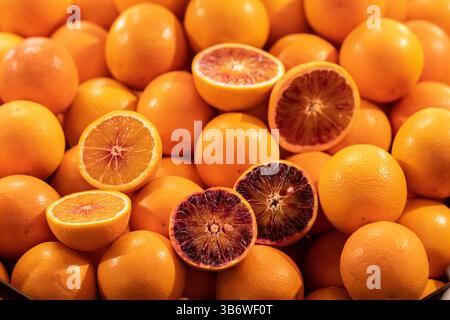 Beautiful oranges displayed in a row on a stall in the fruit and vegetable market with some oranges cut open in half Stock Photo