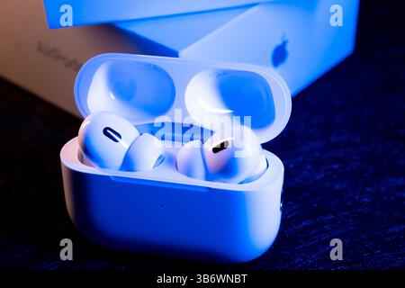 Jurmala, Latvia - 01.05.2025: Apple Headphones - AirPods Pro 2. Wireless Earbuds in Charging Case on Dark Surface With Blue Lighting and Product Stock Photo