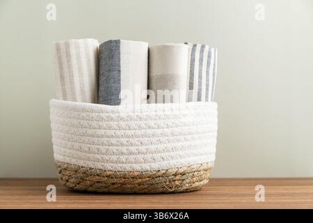 Stack of cotton kitchen towels in wicker basket on table Stock Photo
