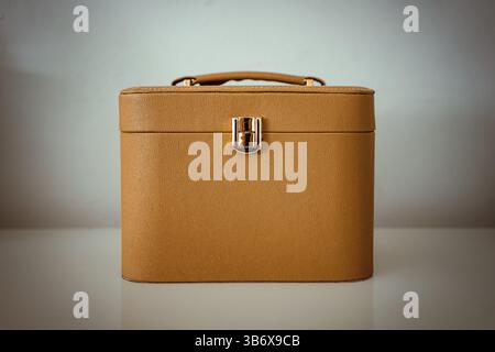 Details of a brown luxury cosmetic bag on a white table in front of a white wall. Stock Photo