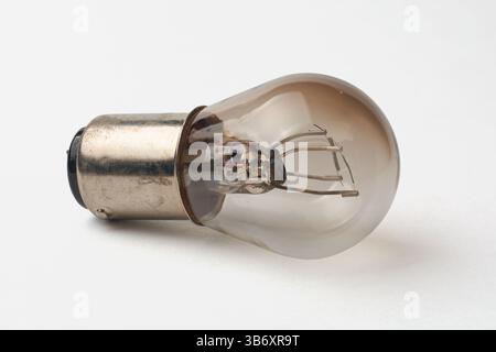 close-up macro view of old used incandescent dual filament light bulb with silver metal base isolated white background, two filaments visible inside Stock Photo