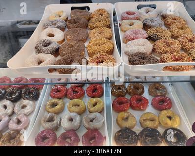 Colored sweet donuts on a tray in a coffee shop bakery. Stock Photo