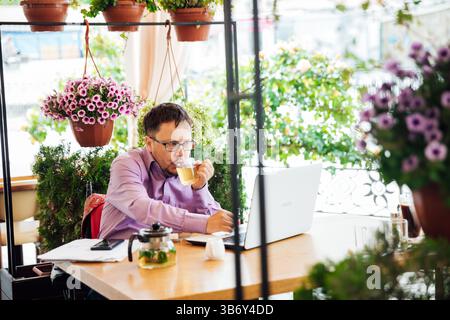 Man working on laptop online at table with food in restaurant Stock Photo