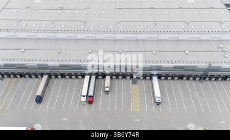 Aerial view of a large warehouse with loading docks and parked trucks. Stock Photo
