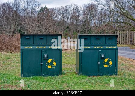 A pair of large metal bear proof environmental garbage bins in a park with compartments for trash plastic and aluminum showing the recyclable symbol Stock Photo