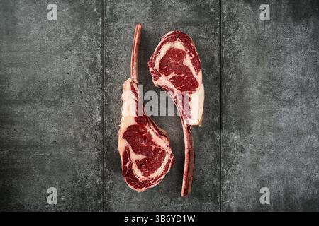 Raw tomahawk steaks on dark stone background Stock Photo