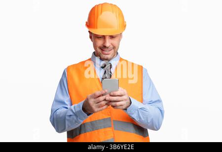 Construction Worker Using Smartphone Standing On White Studio Background Stock Photo