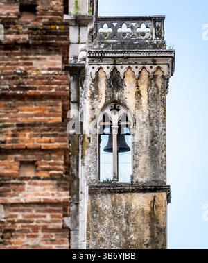 A close-up view of a weathered bell tower with intricate architectural details, featuring a bell visible through a gothic-style window. The tower is p Stock Photo