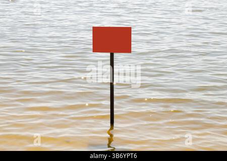 Lonely red empty warning sign on the water in the Dnieper river in Ukraine in the summer, a plate in the water for text Stock Photo