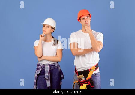 Renovation Planning . Portrait Of Pensive Young Couple In Protective Hard Hats Stock Photo