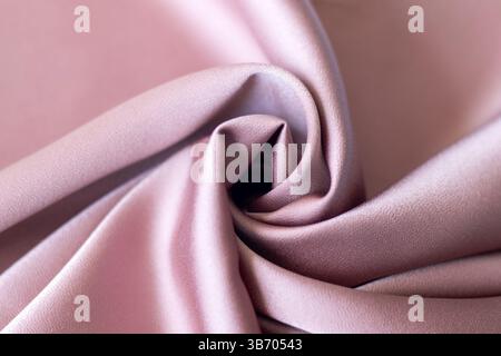 Soft pink satin fabric with elegant folds forming a smooth and refined texture Stock Photo