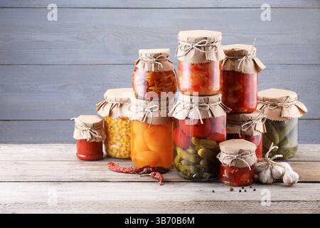 Many jars with different pickled products on wooden table Stock Photo