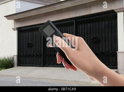 Woman using remote to control electric gate outdoors, closeup Stock Photo