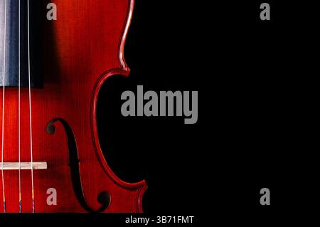 A close-up of the right side of a violin on a black background with copy space on the right Stock Photo