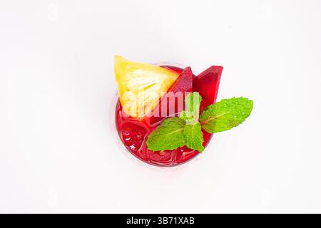red beet or berry smoothie with pineapple slice and mint garnish served in transparent glass on white background. High quality photo Stock Photo