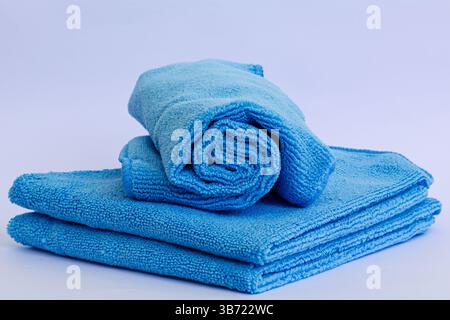 Rolled blue microfiber towel with low pile height on stack of towel isolated on white background Stock Photo