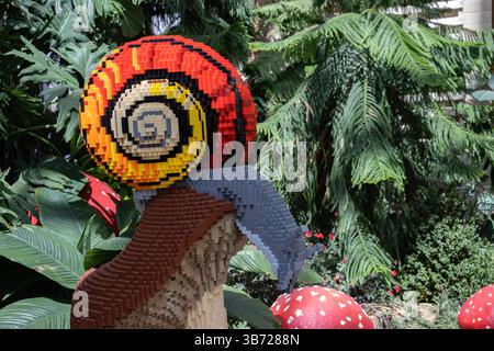 A sculpture of a colorful snail on a mushroom made from Lego bricks is surrounded by plants at Lauritzen Gardens in Omaha, Nebraska, USA. Stock Photo