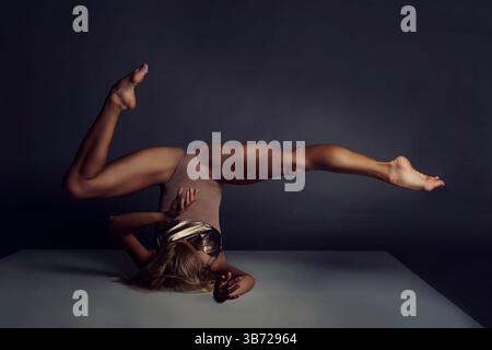 a ballerina in a bodysuit stands on her shoulders doing a cross splits with her feet up Stock Photo