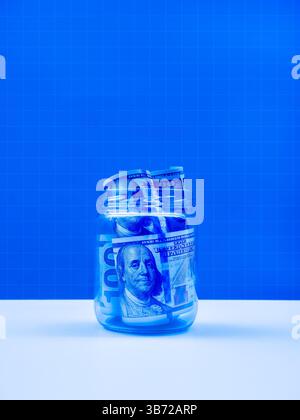 100 dollars bill banknotes, money cash inside glass jar isolated on white table and blue grid network, vertical background. Savings money, digital mon Stock Photo