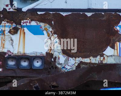 Rust on the front hood of an old car, close-up. An old abandoned rusty white car with damaged paint on the bumper and hood. Stock Photo