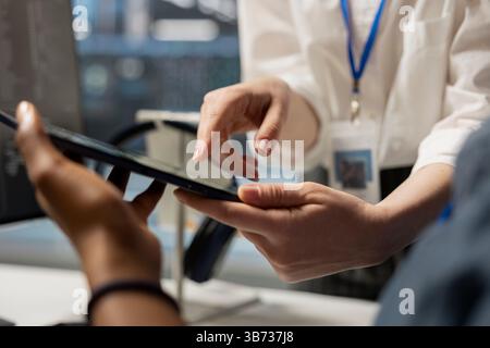 Data center engineering team analyzing software logs metrics on tablet, optimizing storage systems. Close up of server farm coworkers inspecting resource utilization on device Stock Photo