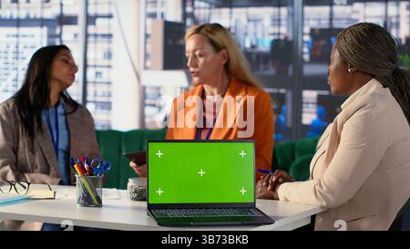 Multicultural team of specialists using mockup copy space in the office, working with resilience to accomplish enterprise objectives. Manager and employees meeting for a briefing. Camera A. Stock Photo