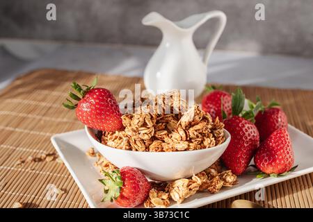 A bowl filled with homemade oat granola and fresh strawberries, offering a colorful and nutritious breakfast choice perfect for a clean and balanced l Stock Photo
