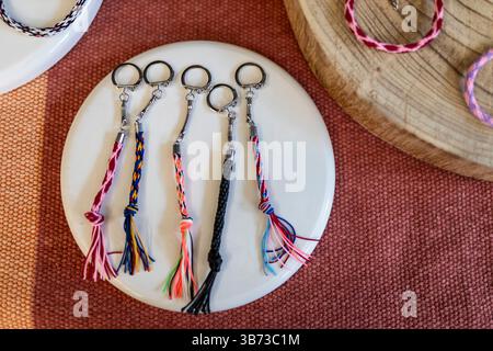 braided keychains with silver rings are displayed on a white surface at a craft market Stock Photo