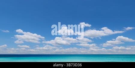 Beautiful seascape featuring a vast expanse of turquoise water under a vibrant blue sky dotted with fluffy white clouds Stock Photo