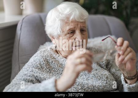 Senior woman holding eyeglasses in her hands Stock Photo