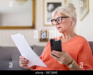 Senior woman looking through financial documents at home Stock Photo