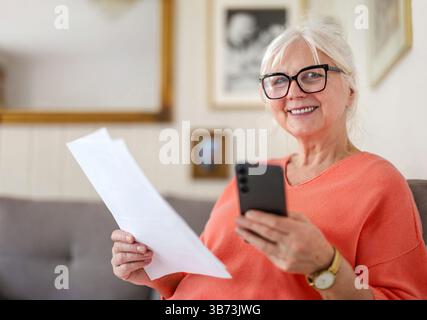 Senior woman looking through financial documents at home Stock Photo