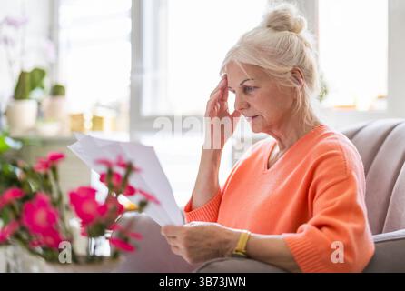 Senior woman looking through financial documents at home Stock Photo