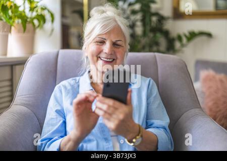 Senior woman using mobile phone at home Stock Photo