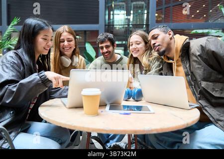 Group of young students working together on laptops, enjoying a collaborative learning experience outdoors Stock Photo