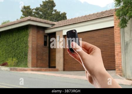 Woman using remote to control electric gate outdoors, closeup Stock Photo