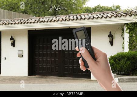 Woman using remote to control electric gate outdoors, closeup Stock Photo