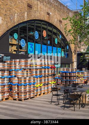 London, United Kingdom - April 28, 2025: Outdoor 3 Locks brewery in Camden town with stacked beer kegs and seating area under a brick viaduct archway. Stock Photo
