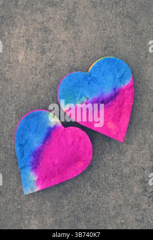 Two felt hjeart shapes dyed bright bl;ue and shocking pink lying on brown sandstone Stock Photo