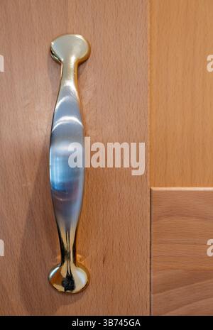 Close up of worn metal handle on wooden cupboard door. Detail of a kitchen cabinet Stock Photo